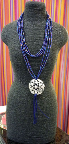 collier de perles bleues &agrave; trois rangs, portant une rosace fantaisie